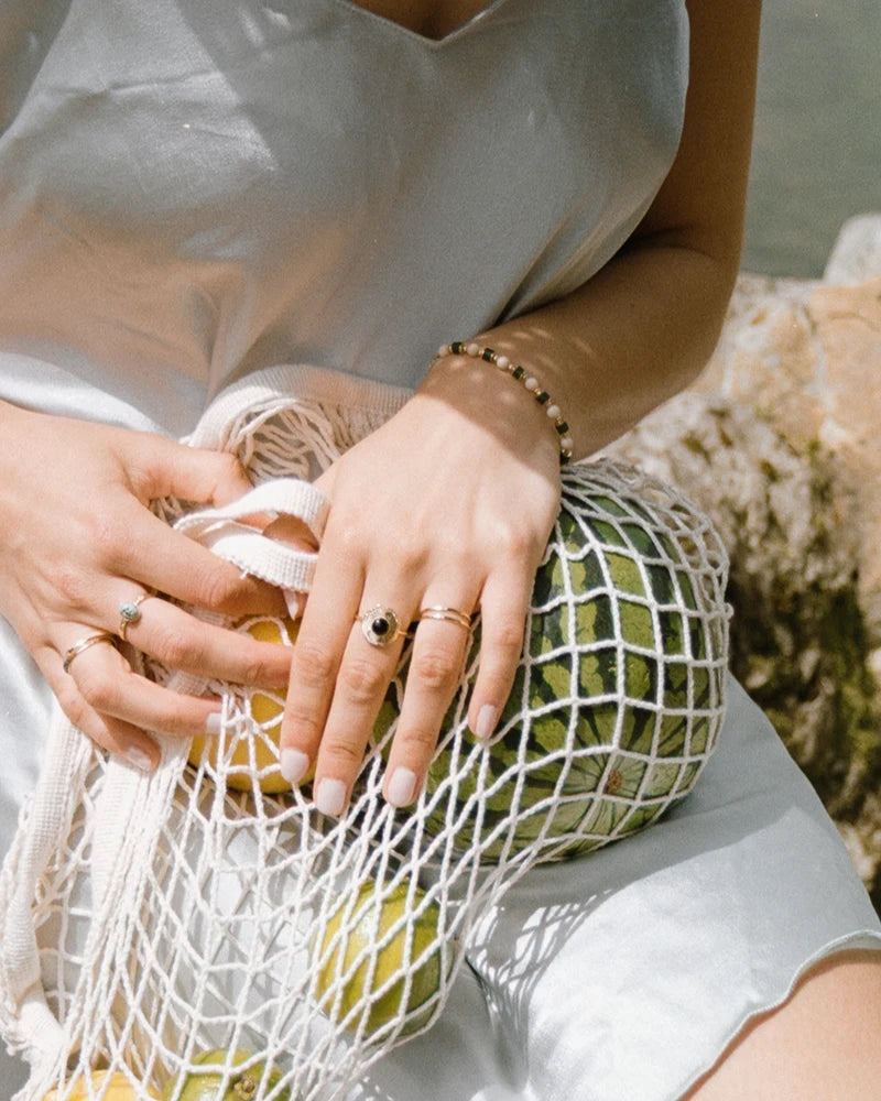 Bracelet Sanjula porté avec une tenue estivale, mis en valeur par une lumière douce et naturelle sur fond de plage et nature.
