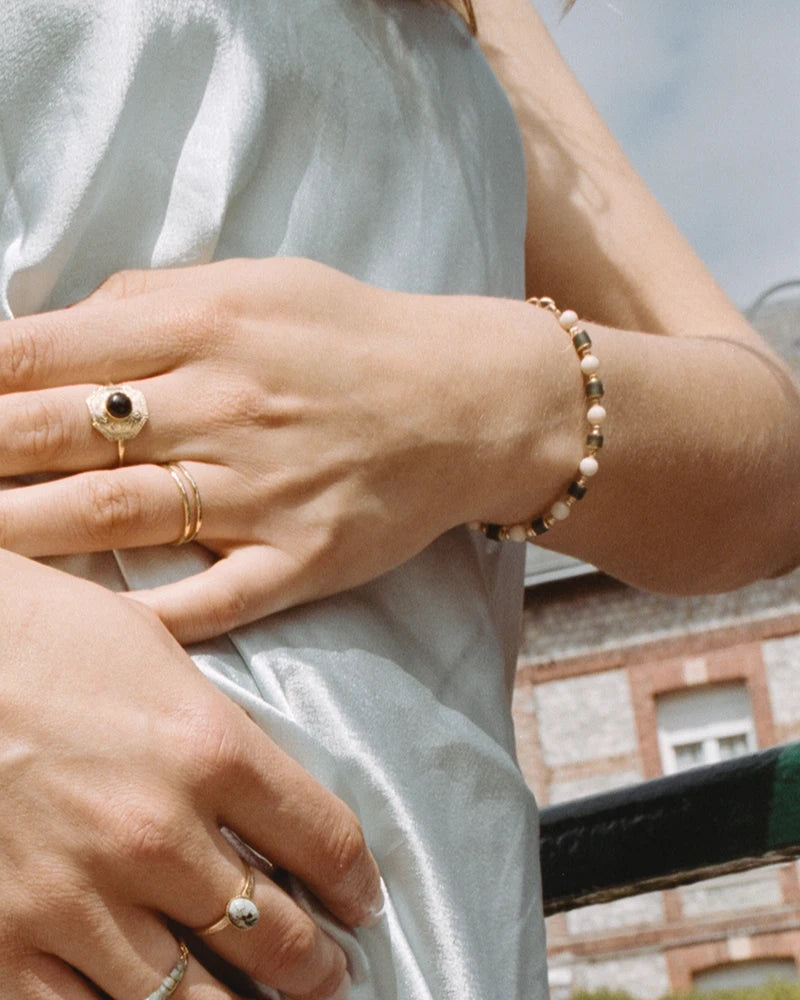 Bracelet Sanjula porté sur une robe satinée, contraste chic entre les textures brillantes et la douceur des perles de verre artisanales.