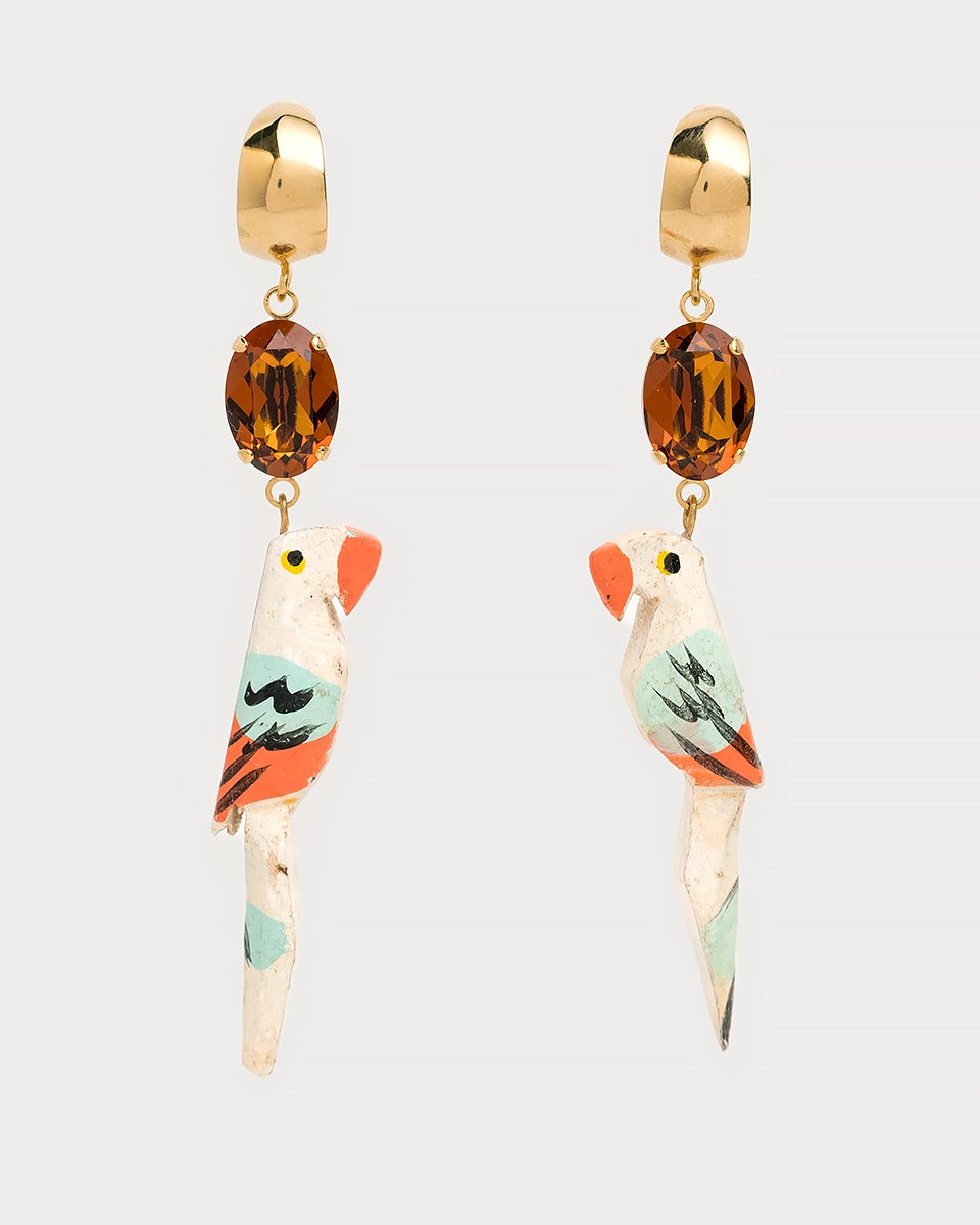 Boucles d'oreilles pendantes originales avec pendentifs en forme de perroquets sculptés et peints à la main, ornées de cristal ovale couleur ambre et attaches dorées.
