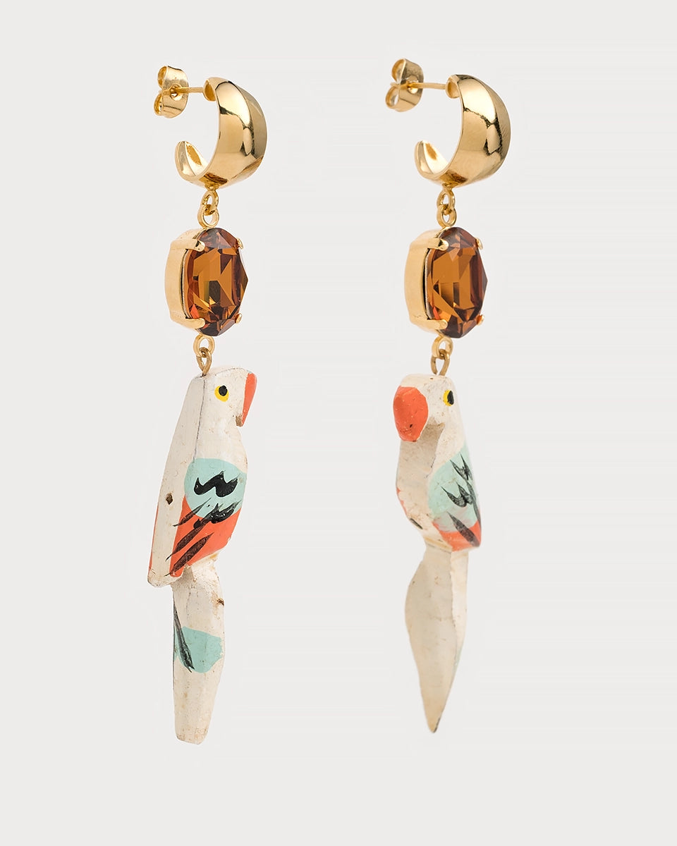 Boucles perroquet en laiton doré avec pierre ambrée et pendentif peint à la main, présentées de côté sur fond blanc.