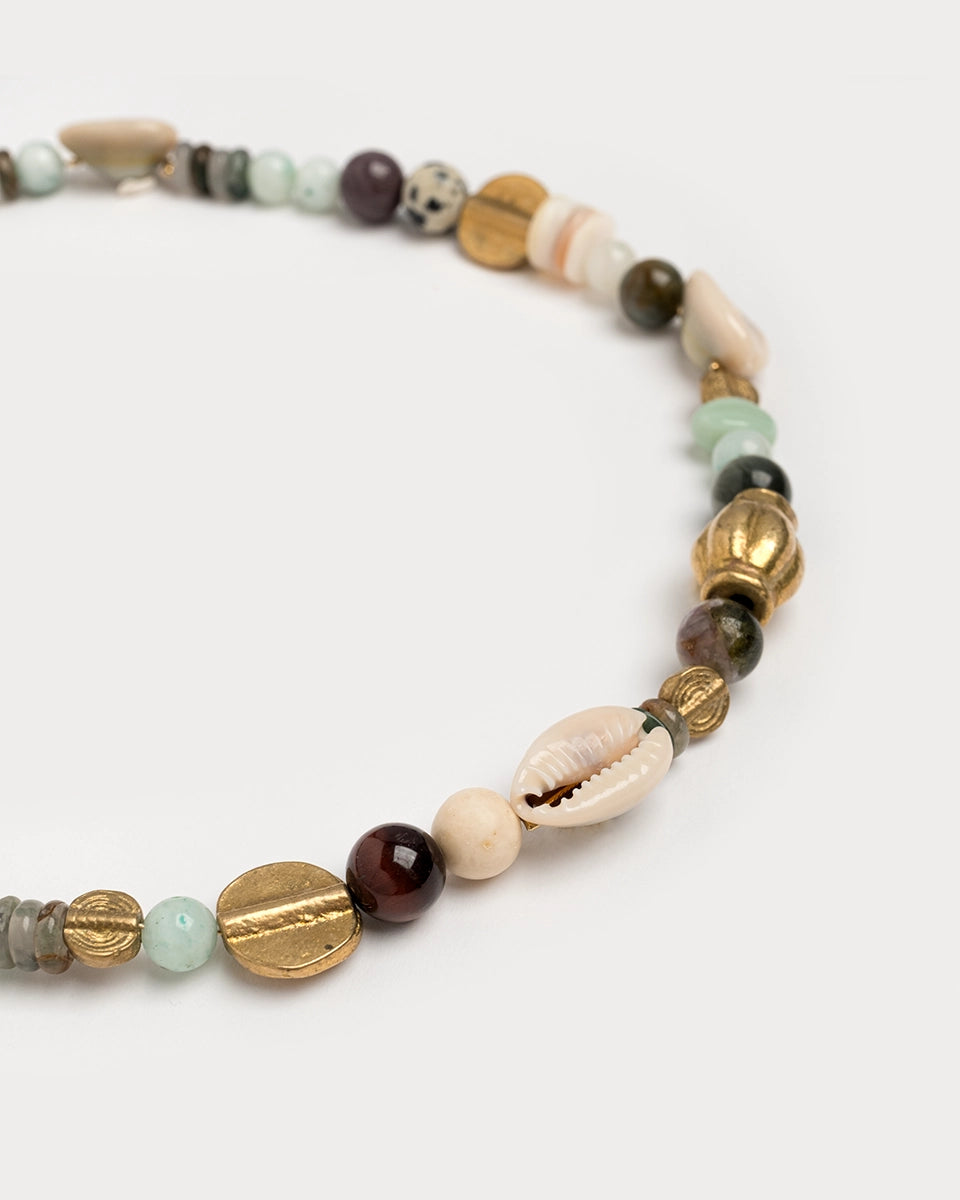 Gros plan studio du collier Samudra, perles naturelles variées, coquillages et éléments dorés sur fond blanc.