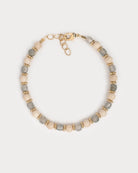 Vue du dessus du bracelet Lavani sur fond clair, mettant en valeur l’alternance délicate entre les pierres naturelles de labradorite et les perles beige nacrées, entrecoupées de perles dorées finement travaillées.