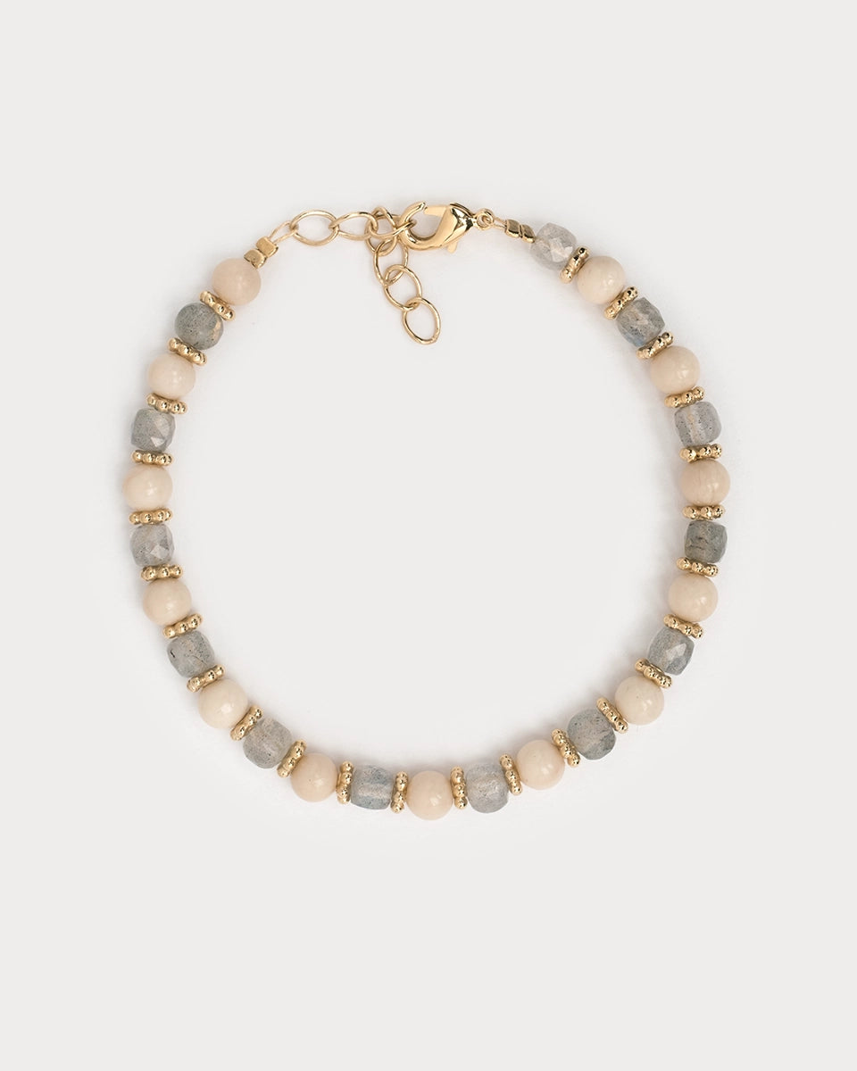 Vue du dessus du bracelet Lavani sur fond clair, mettant en valeur l’alternance délicate entre les pierres naturelles de labradorite et les perles beige nacrées, entrecoupées de perles dorées finement travaillées.