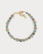 Bracelet Urja à perles de verre colorées et détails dorés, capturé en vue rapprochée sur fond blanc neutre, mettant en valeur les nuances bleu-vert et or.